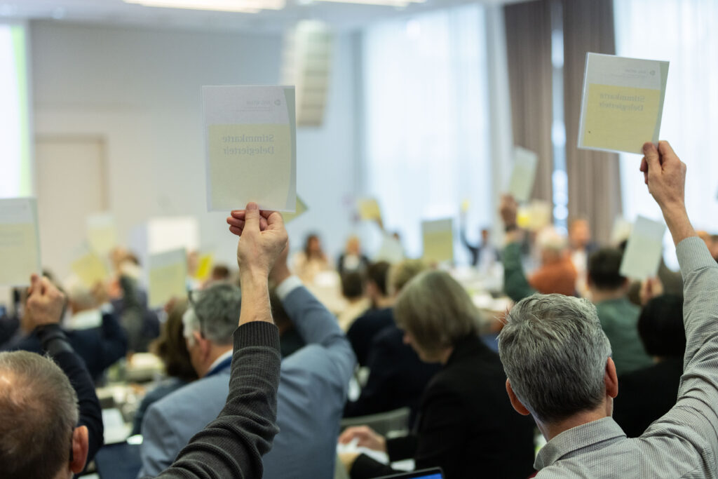 Verschiedene Personen bei einer Abstimmung auf der 56. Delegiertenversammlung