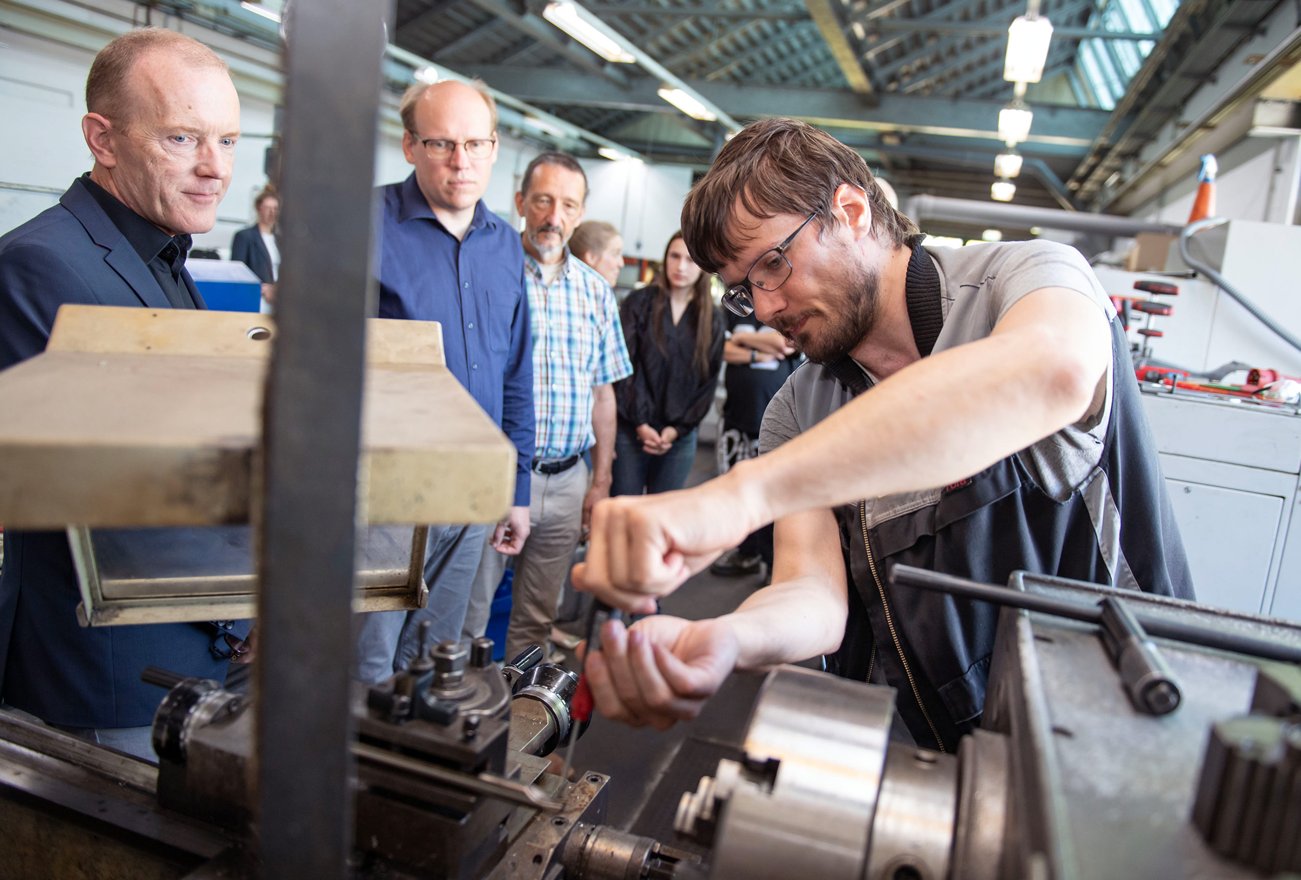 Personen in einer Werkstatt an einer Maschine