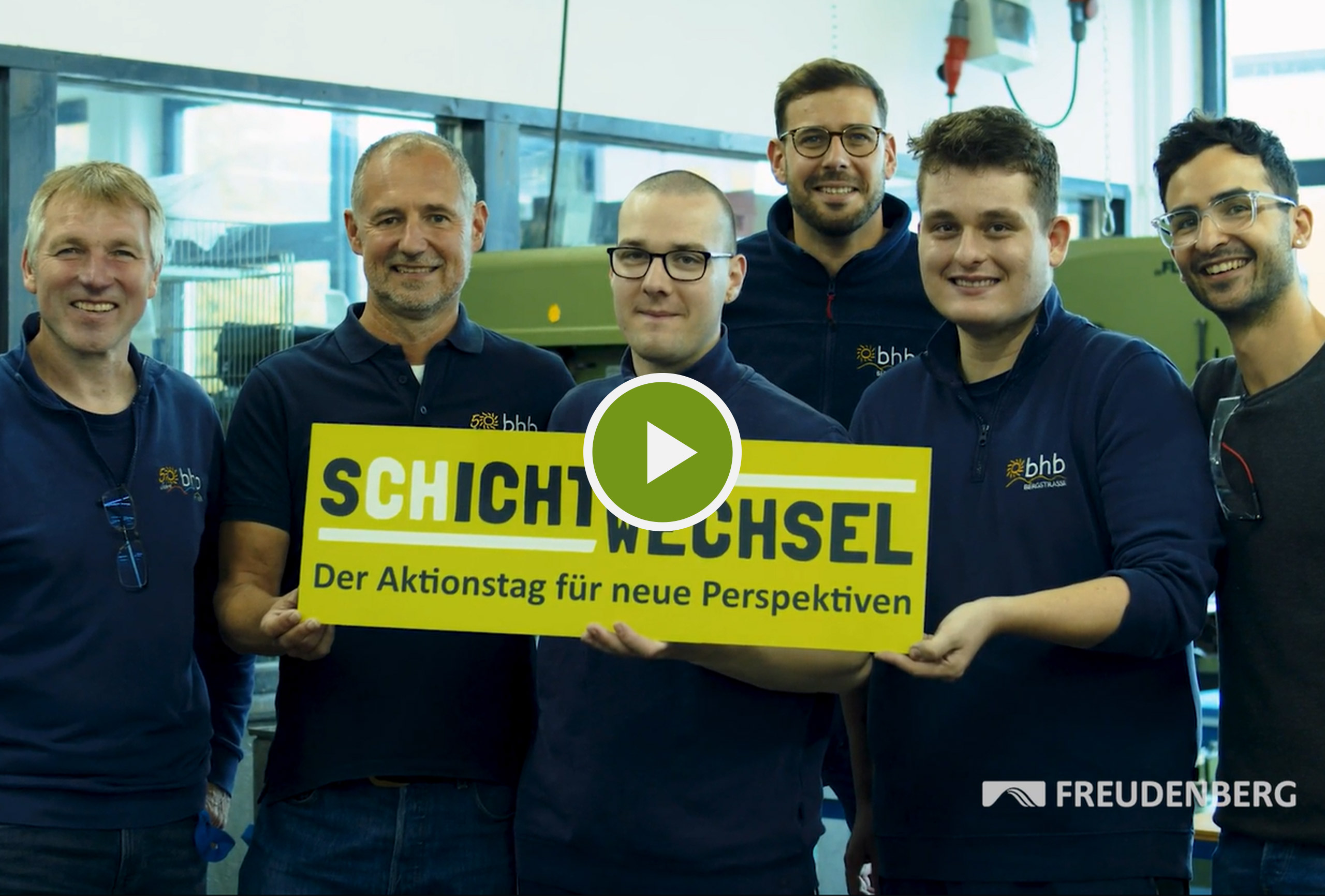 Das Foto zeigt 5 Männer, die in die Kamera lächeln und ein Schild halten auf dem steht: Schichtwechsel. Der Aktionstag für neue Perspektiven.