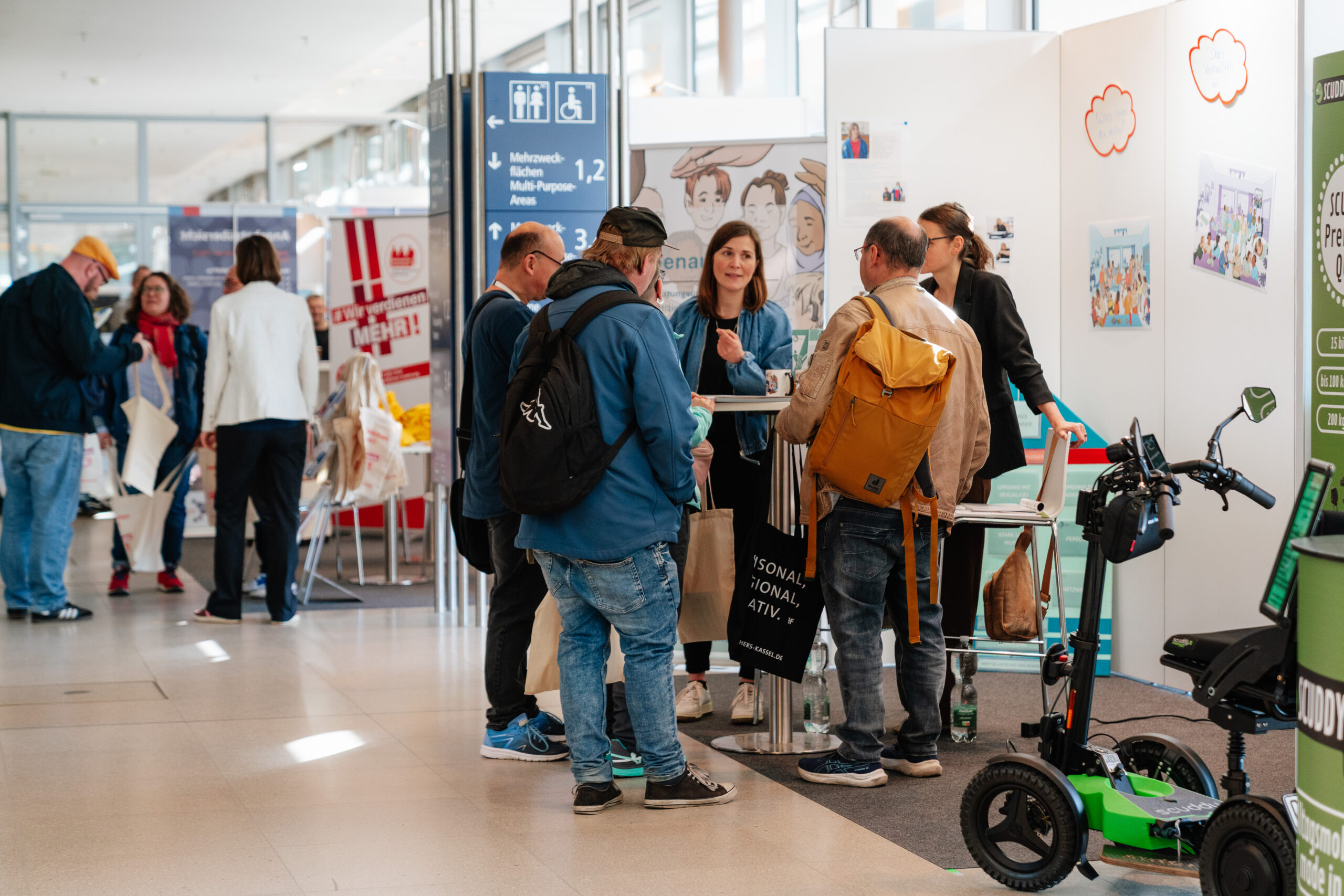 Das Foto zeigt eine kleine Gruppe vorn Menschen. Sie stehen um einen Stehtisch an einem Messestand und unterhalten sich.