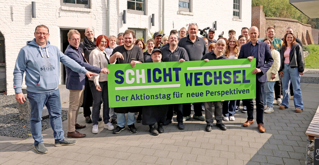 Beschäftigte der Lebenshilfe HEinsberg halten ein Schild mit dem Logo des Aktionstags Schichtwechsel.