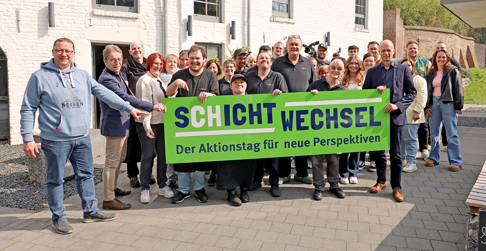 Beschäftigte der Lebenshilfe HEinsberg halten ein Schild mit dem Logo des Aktionstags Schichtwechsel.