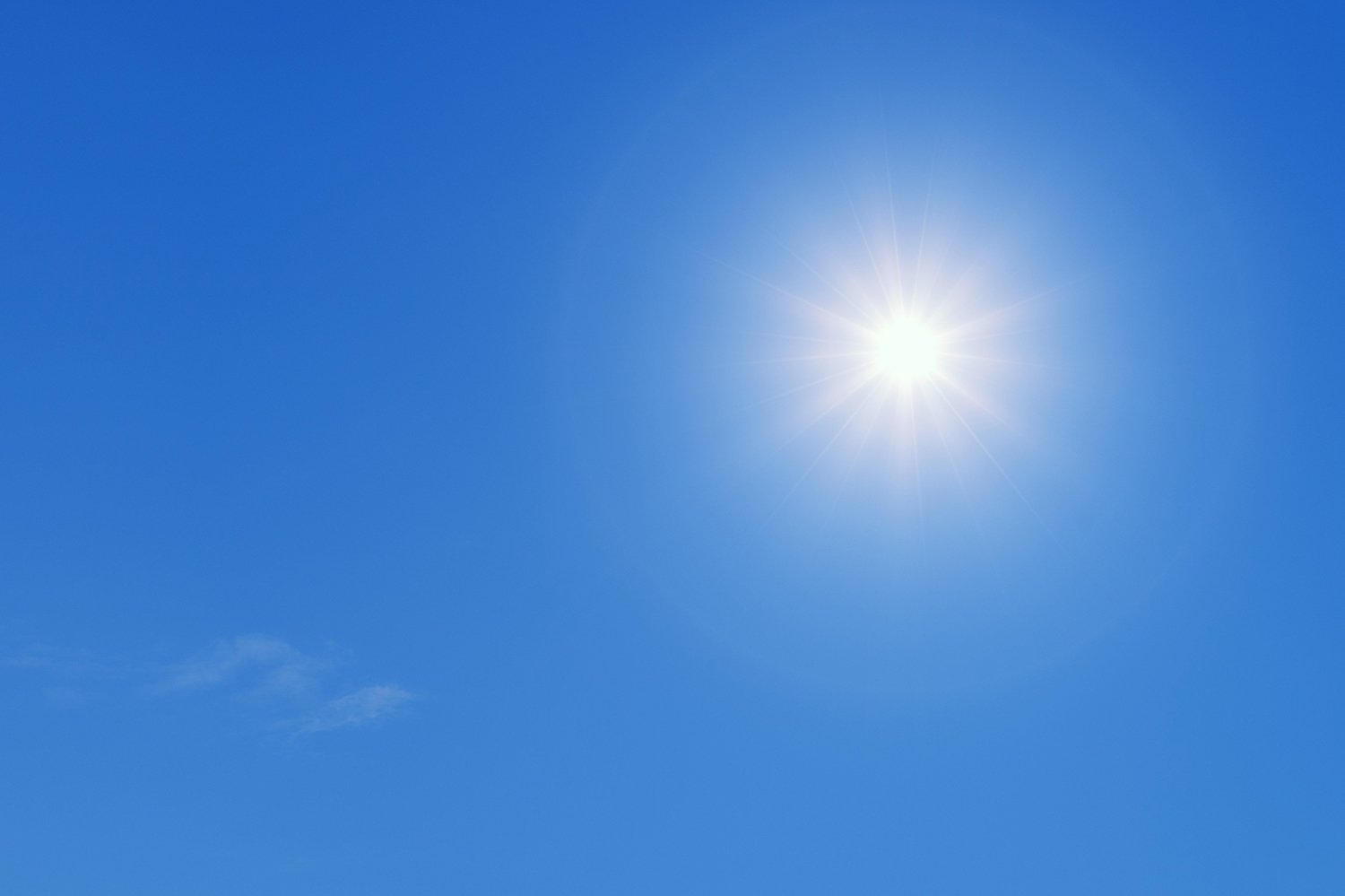 Das Foto zeigt einen wolkelosen Himmel. In der oberen rechten Ecke ist die Sonne, die ein grelles Licht wirft.